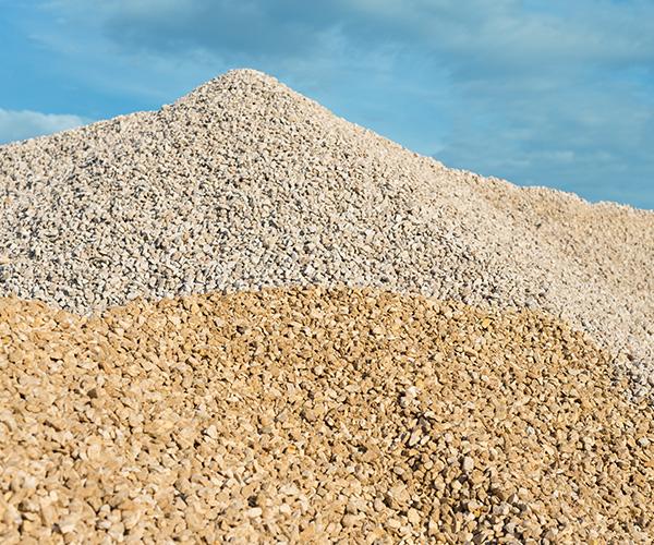 Home 86 Pilhas de agregados reciclados (areia, brita e rachão) em tons terrosos e cinzas, representando materiais sustentáveis da Multilix para construção e economia circular.