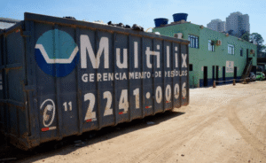 Blog 15 Caçamba estacionária azul com logo Multilix em grande área de obra, usada para descarte de resíduos com gerenciamento sustentável da construção civil.