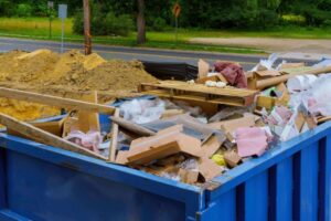 Blog 16 Caçamba cheia de entulho de obra em via urbana e trabalhadores descarregando materiais, representando gestão sustentável de resíduos com a Multilix, expert em reciclagem e destino correto.