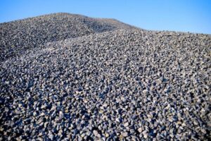 Blog 6 Foto em plano detalhado de uma pilha de Brita Graduada Simples da Multilix, composta por pedras pequenas cinzas e granulometria uniforme, sob céu azul.